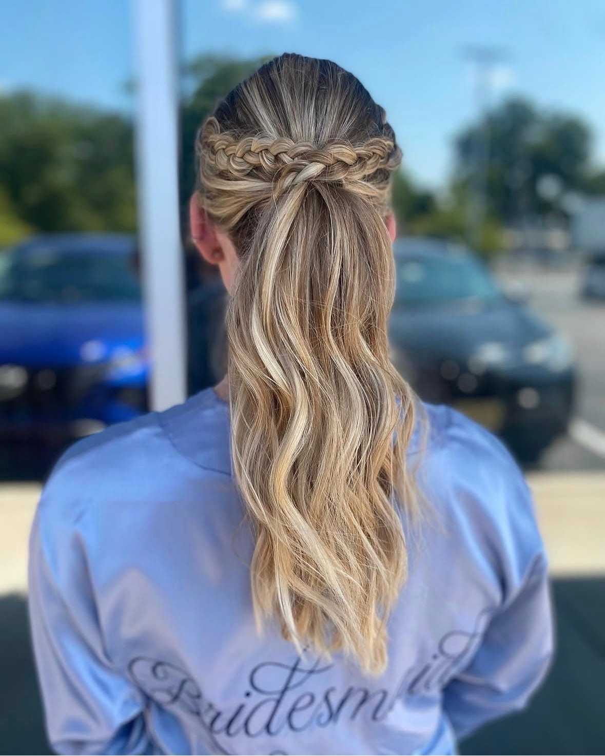 Bridesmaid with a braided half-up hairstyle outside a building.
