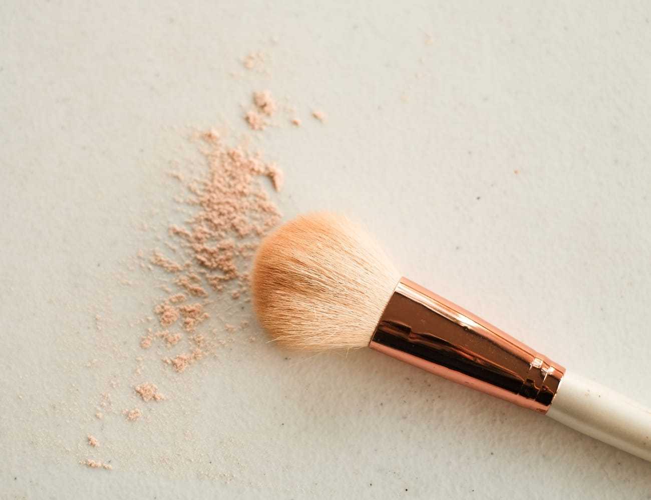Makeup brush with loose powder on a white surface.