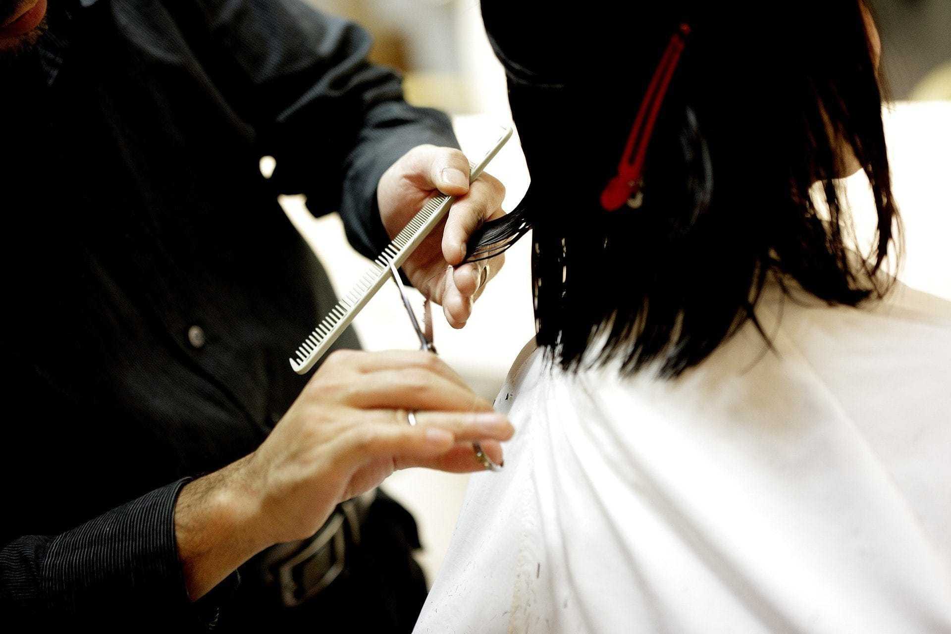 Hairdresser cutting client's hair with scissors in a salon.