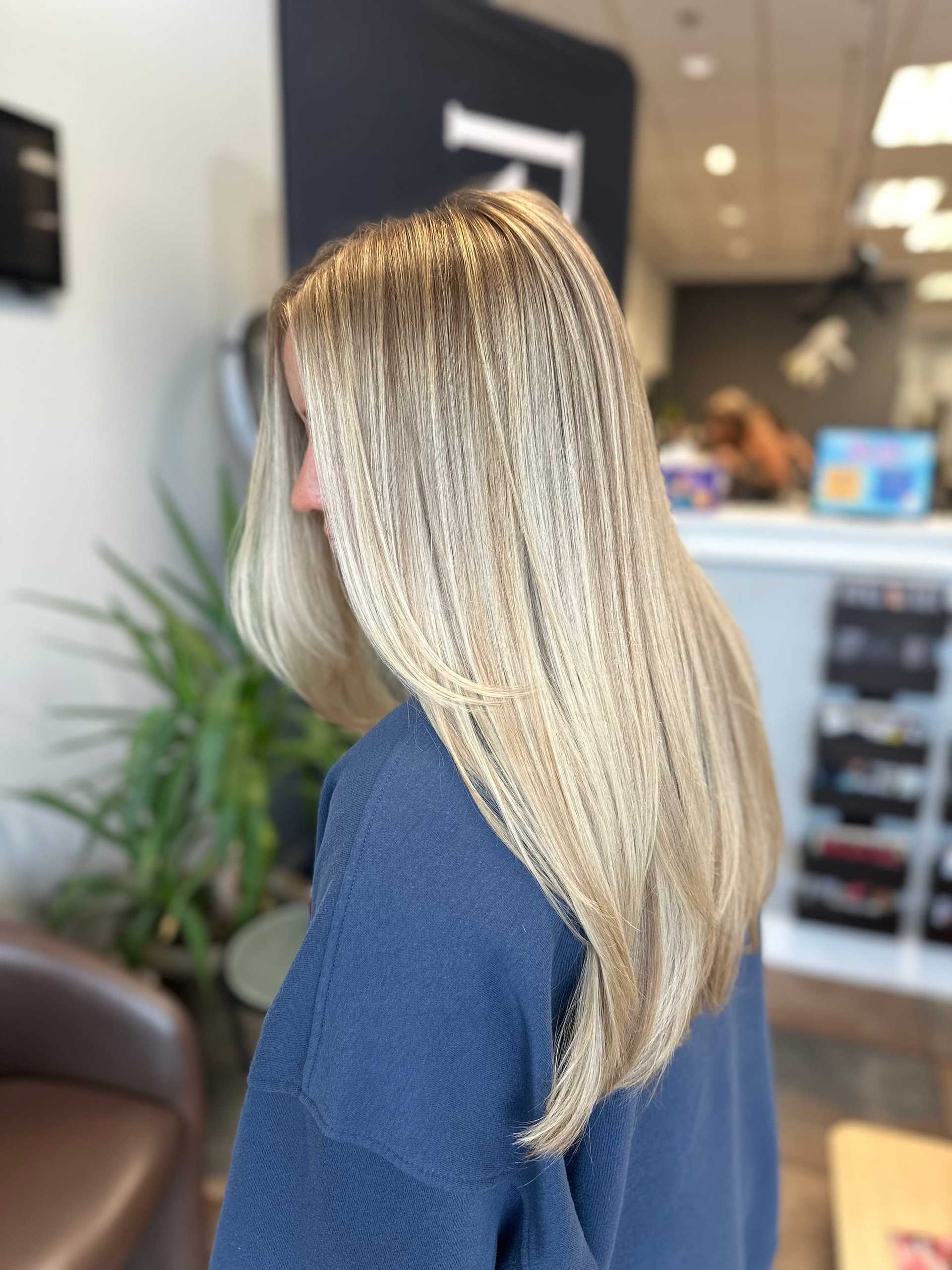 Blonde-haired person with smooth, sleek hairstyle in a modern salon setting.